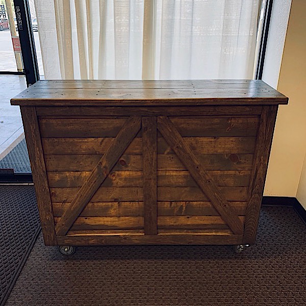 A rustic 5-foot rolling bar made of solid wood, featuring a built-in ice bucket, speed rail, and cutting board, ideal for elegant event setups.